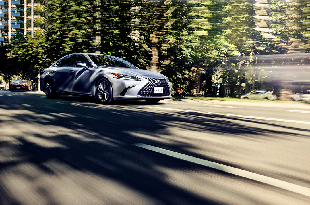 A silver ES 300h speeds across a street, everything else is blurred.