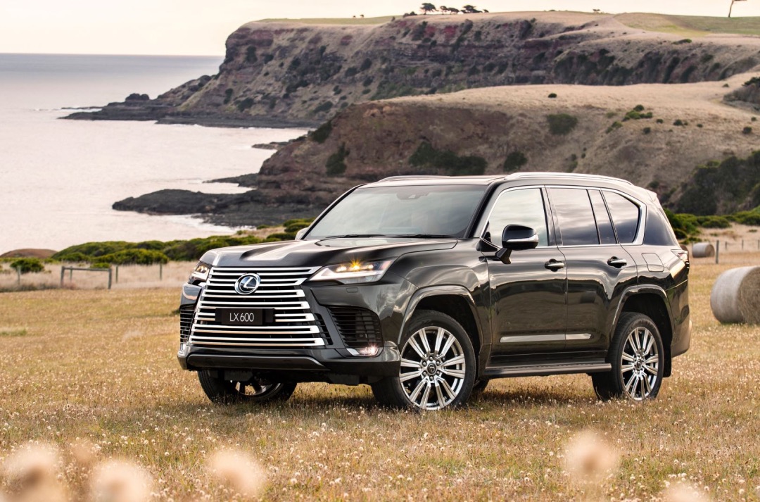 Black Lexus LX parked on a dry hill, cliffs and the ocean can be seen in the background.