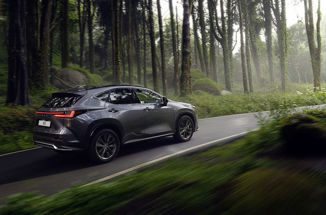 Lexus NX 450h+ driving through a green forest