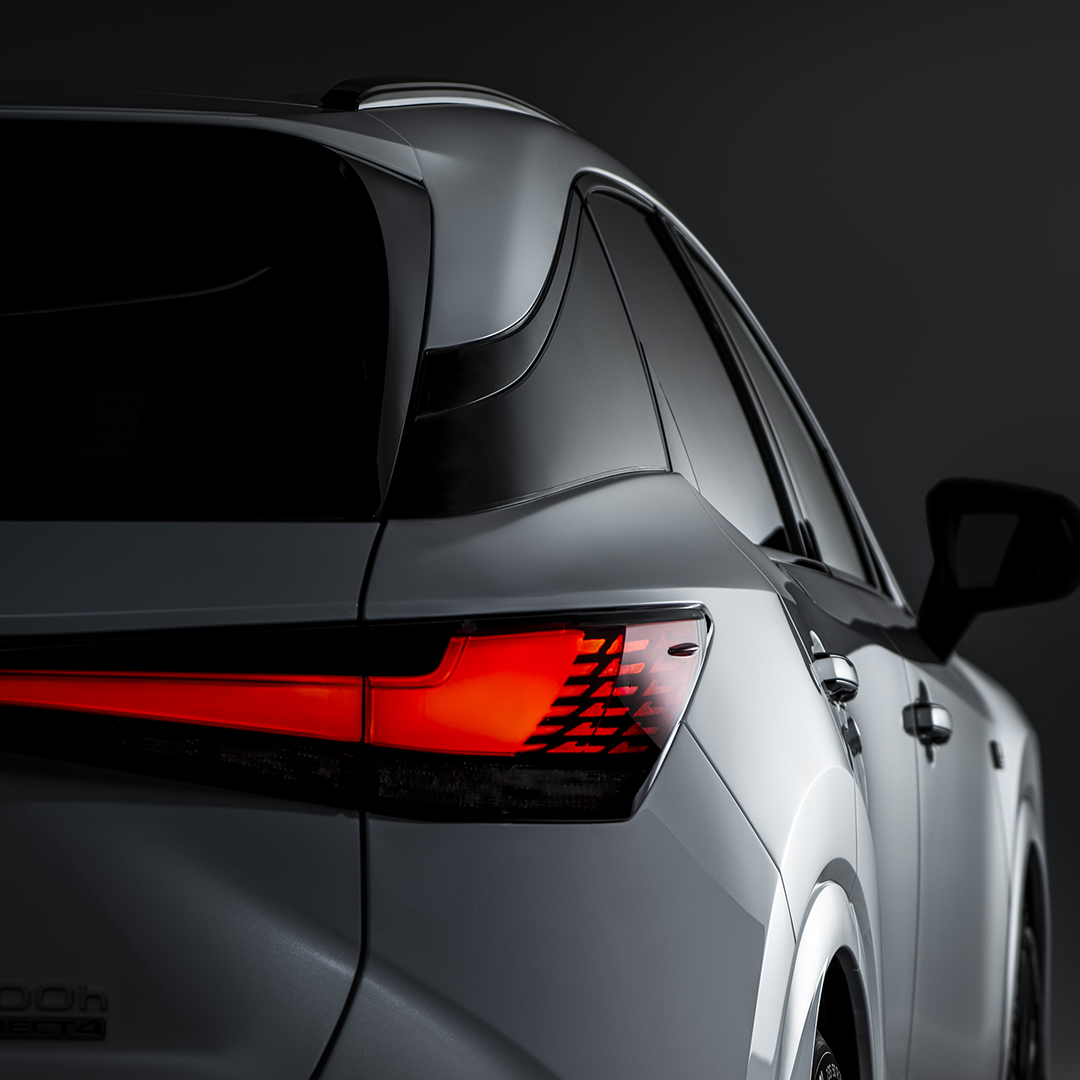 The rear exterior light of the Lexus RX is lit, the rest of the vehicle in shadow.