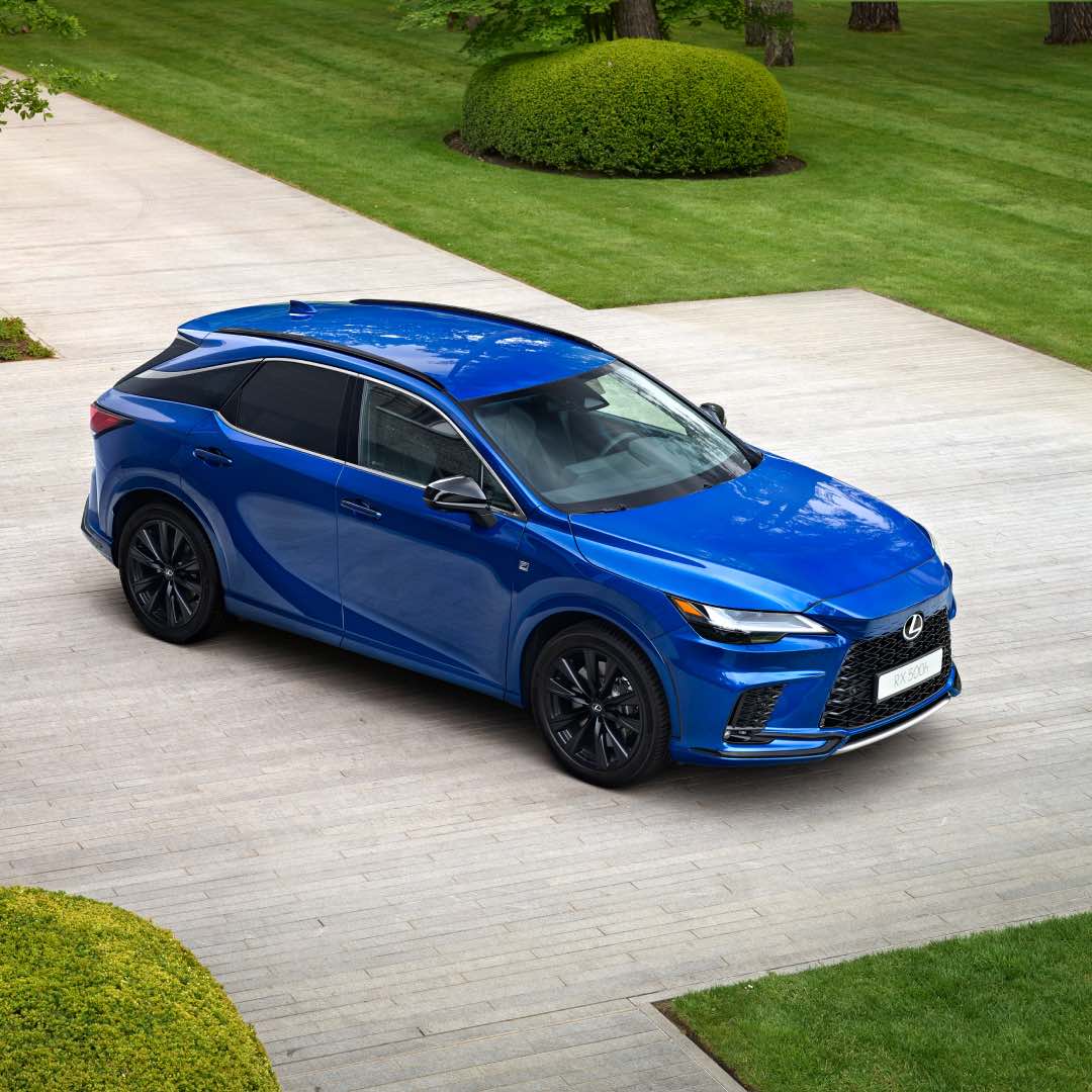 A Sapphire blue RX sits on a concrete driveway, greenery around it.