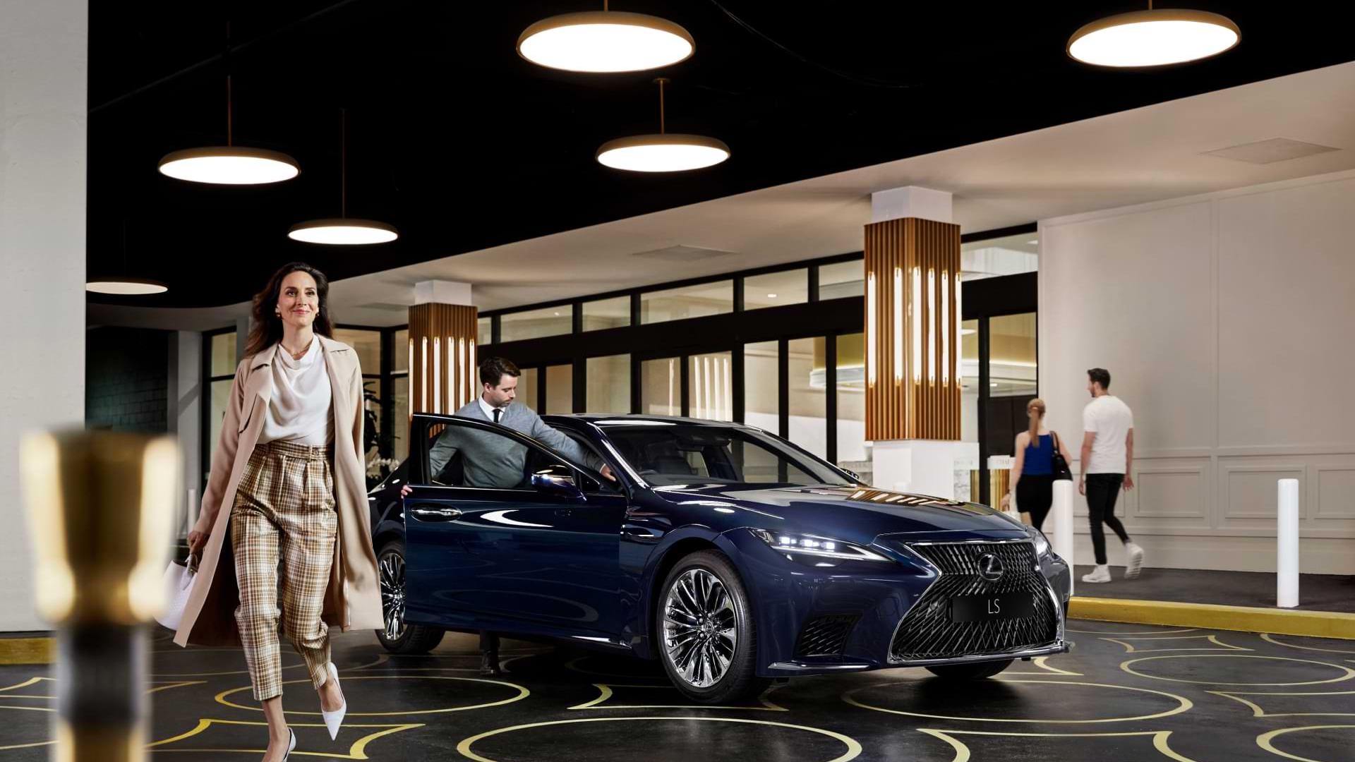 Lady walks away from a blue Lexus LS. A valet gentleman climbs into the vehicle to park in Valet parking at Chadstone.