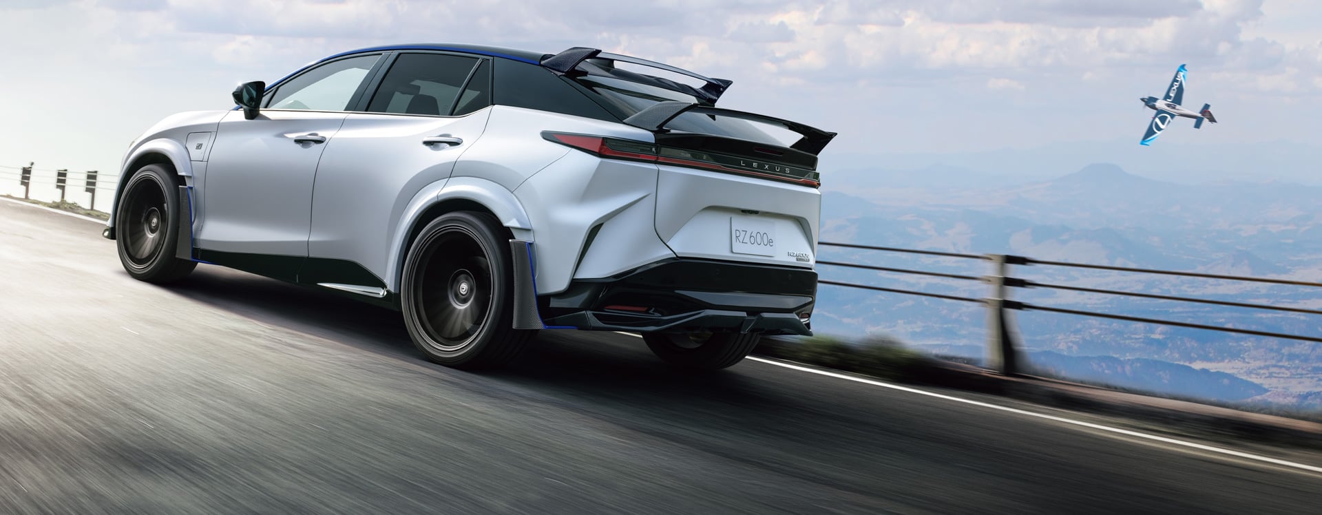 A white Lexus RZ 600e F Sport Performance driving on a mountain road.
